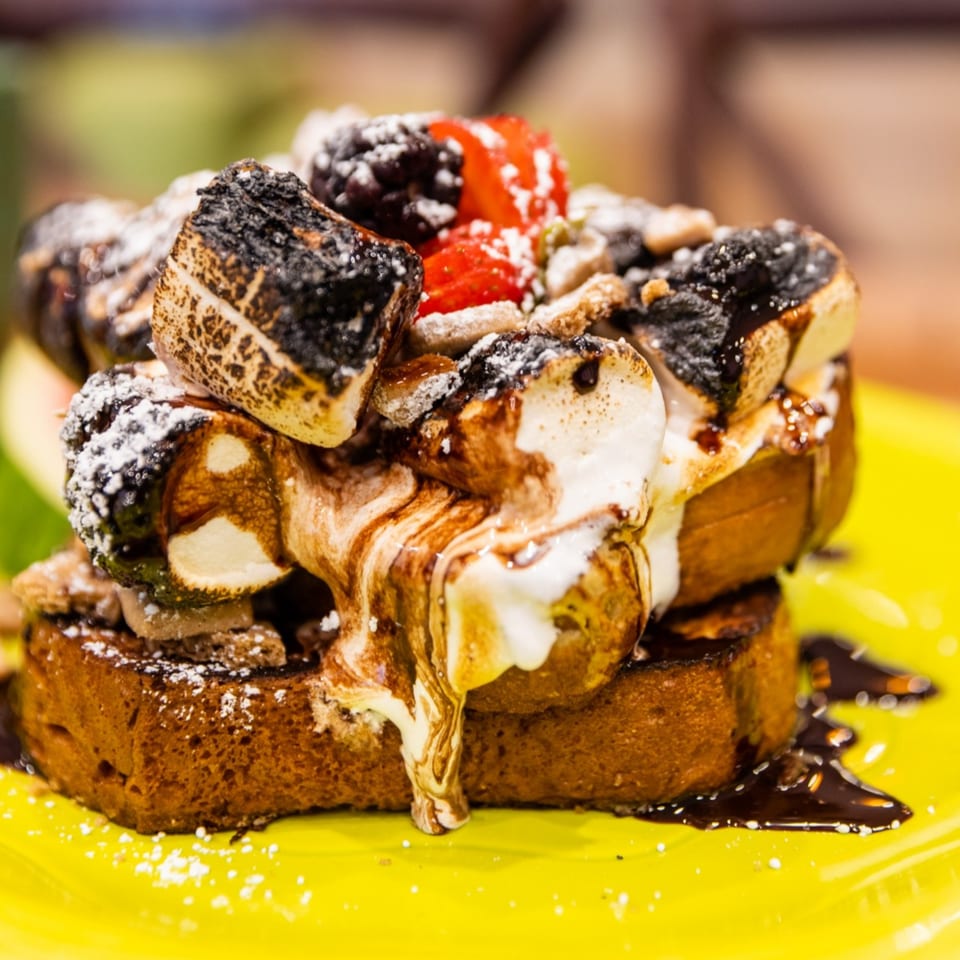 Lou's Coffee Shop's French toast topped with toasted marshmallows, berries, and chocolate drizzle.